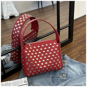 Detail of red leather shoulder bag with silver studs on denim jacket background