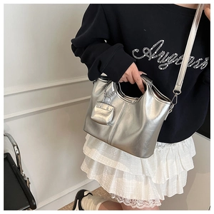 Close-up of metallic silver tote bag with mini charm pouch and adjustable strap detail