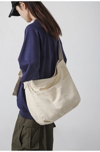 Detail view of large beige canvas bag with deep front pocket and wide shoulder strap