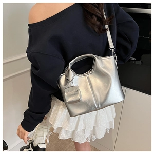 Detail of silver metallic handbag with smooth mirror finish and square mini charm
