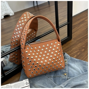 Close-up of caramel leather shoulder bag with silver studs on blue denim jacket