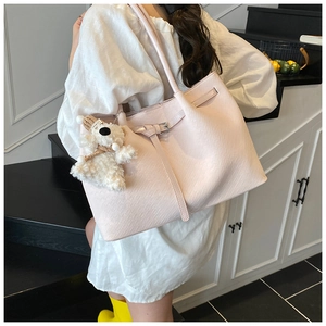 Detail view of pink woven tote bag with metallic buckle and cute plush puppy charm