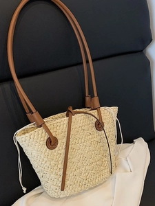 Cream woven straw tote bag with brown leather straps and drawstring closure in main view
