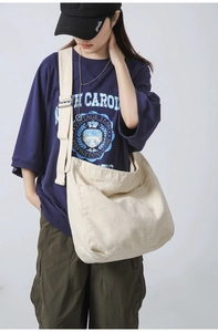 Detailed view of the large capacity cream canvas messenger bag showing natural drape on model