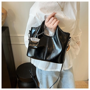 Detail of black glossy bucket bag with mini pouch and silver chain strap for women