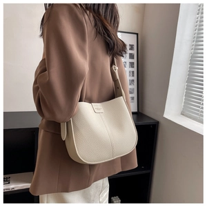 Close-up of cream textured leather shoulder bag with decorative strap and buckle