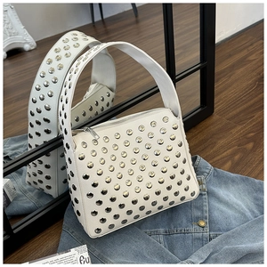 Detailed macro view of silver metallic studs on a white leather punk style shoulder bag