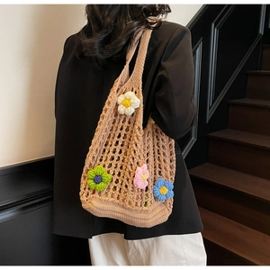 Detail of hand-crocheted hollow shoulder bag featuring 3D floral accents on a model