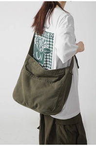 Detail of dark green canvas tote bag showing side pocket and large capacity on model