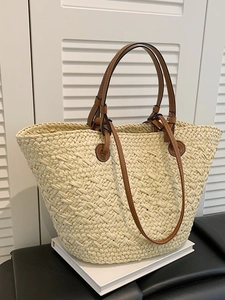 Fashionable beige woven straw tote bag with brown leather handles and a long shoulder strap