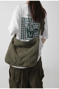 Rear view of an olive green canvas messenger bag worn by a model for a casual look