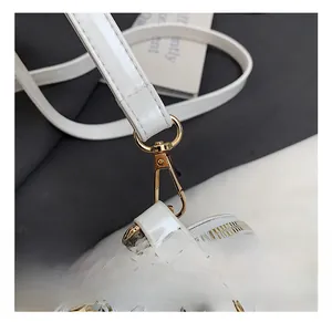 Close-up of golden metal hooks and zipper on a white patent leather shell bag