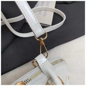 Detail of white patent leather texture with gold metal hook and zipper on a shell bag