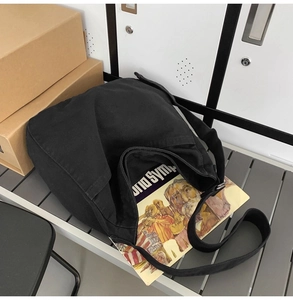 Detail view of black canvas tote bag showing wide shoulder strap and spacious interior