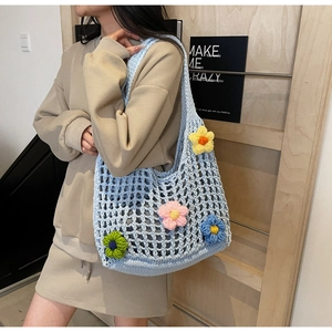 Close-up of light blue crochet bucket bag with colorful 3D floral accents on a model