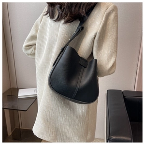 Close-up of black litchi grain leather crossbody bag with adjustable wide strap on model