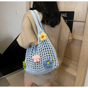 Detail of light blue crochet shoulder bag with colorful 3D knitted floral decorations