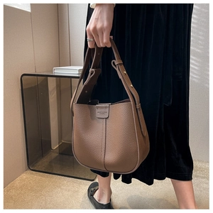 Close-up of brown lychee-pattern leather texture and brand detail on bucket bag