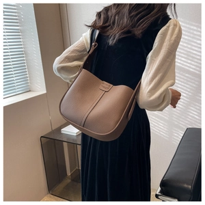 Detailed side view of brown lychee grain leather crossbody bag with adjustable strap