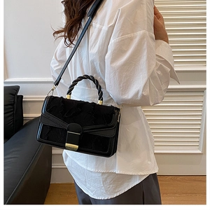 Dettaglio borsa nera in pelle con texture in tessuto sfrangiato e chiusura in oro lucido