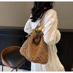 Detail of hollow-out straw shoulder bag with colorful ethnic style woven wide strap