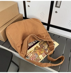 Detailed view of spacious brown canvas tote bag with wide strap holding books