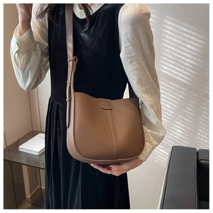 Detailed close-up of brown lychee-pattern leather crossbody bag with stitching and strap