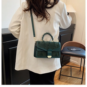 Dettaglio borsa a tracolla vintage verde scuro con trama sfrangiata e manici intrecciati