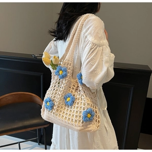 Detail of hand-woven hollow tote bag with 3D floral accents and wide shoulder strap