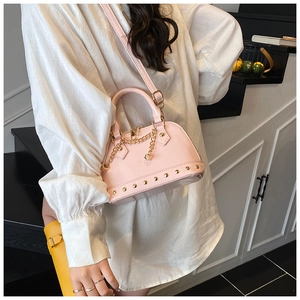 Close-up of pink patent leather shell bag with gold rivet details and dice chain charm