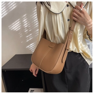 Detail of the brown pebble leather crossbody bag showing the logo and adjustable strap