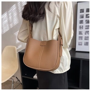 Detail of brown litchi grain leather crossbody bag with adjustable wide strap and logo flap