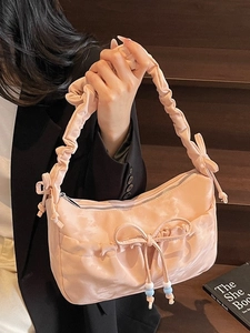 Borsa hobo in raso rosa con manico arricciato e fiocco su uno sfondo in legno chic
