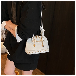 Detail view of white shell bag featuring gold chain tassels and metallic rivet accents