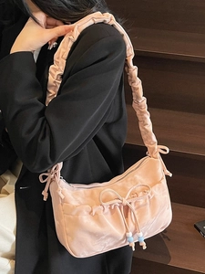 Borsa hobo rosa a pieghe con fiocco e coulisse di perline indossata su una scala
