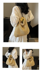 Detail of straw tote bag featuring a woven texture and a black-and-white striped scarf handle