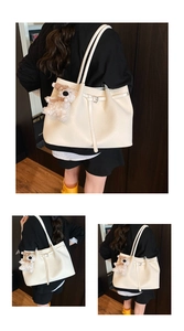 Detailed close-up of cream white woven bucket tote bag with cute teddy bear charm