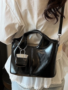 Glossy black trapezoid handbag with silver lock charm and crossbody strap