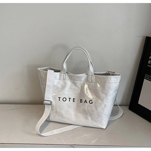 Close-up of minimalist white tote bag showing DuPont paper texture and long strap