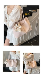 Detail view of pink woven tote bag featuring a leather buckle strap and plush bear charm