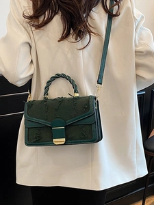 Elegante borsa a tracolla verde scuro ricamata con manico intrecciato indossata da modella