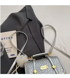Detail of silver woven texture handbag with gold metal plaque and faux fur pompom charm