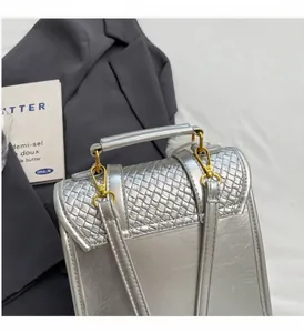 Detail of silver metallic textured handbag with gold hardware and woven leather pattern