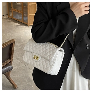Detailed close-up of a quilted white leather crossbody bag with gold chain strap