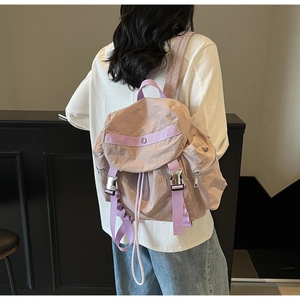 Detail of light purple nylon backpack showing silver buckle and side zipper pocket