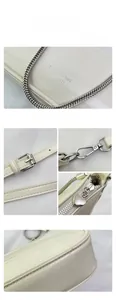 Detail of creamy white patent leather bag with silver chain and heart-shaped zipper