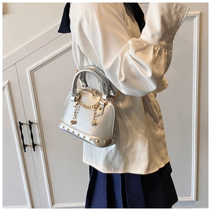 Silver metallic shell bag with gold stud trim and chain strap shown on a model