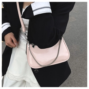 Close-up of pink patent leather underarm bag with silver chain and heart-shaped zipper