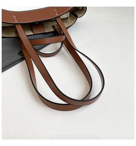 Close-up of brown leather tote bag with white contrast stitching and handle detail