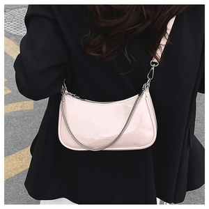Street style shot of a pink patent leather underarm bag with silver chain on model
